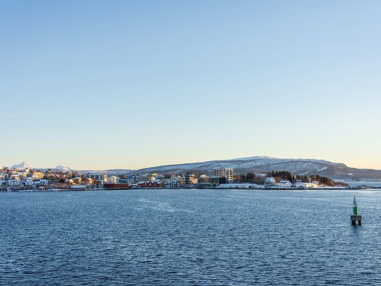 Finnsnes, Norwegen - Stadt am Wasser mit gr&uuml;nem Leuchtfeuer und Bergkulisse