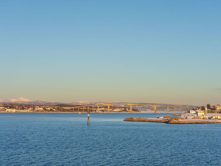 Finnsnes, Norwegen - Br&uuml;cke &uuml;ber Fjord mit K&uuml;ste und H&auml;usern im Abendlicht