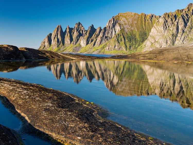 Finnsnes, Norwegen - Markante Felsberge &uuml;ber stillem See mit klarer Spiegelung