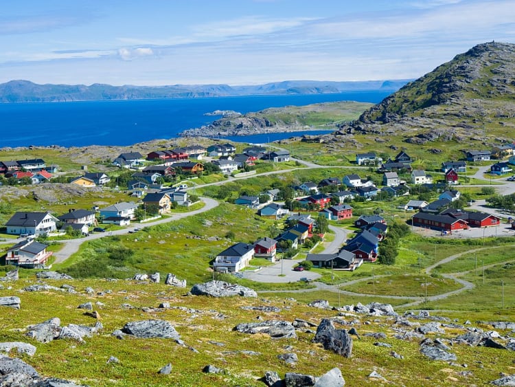 Hav&oslash;ysund, Norwegen - K&uuml;stenort mit bunten H&auml;usern auf gr&uuml;nen H&uuml;geln am Meer