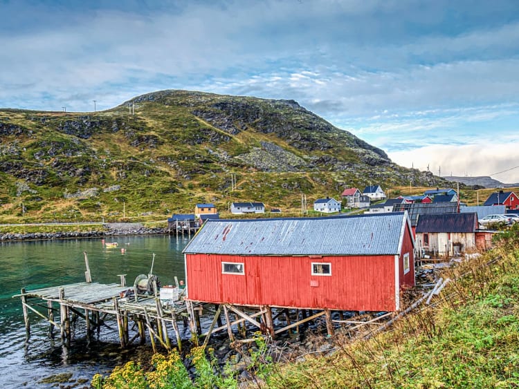 Hav&oslash;ysund, Norwegen - Rotes Haus auf Stelzen am Wasser mit Steg und H&uuml;geln