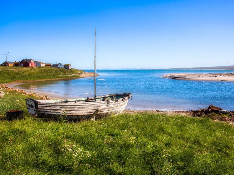 Vads&oslash;, Norwegen - Kleines Boot am Ufer vor ruhigem Wasser und bunten H&auml;usern