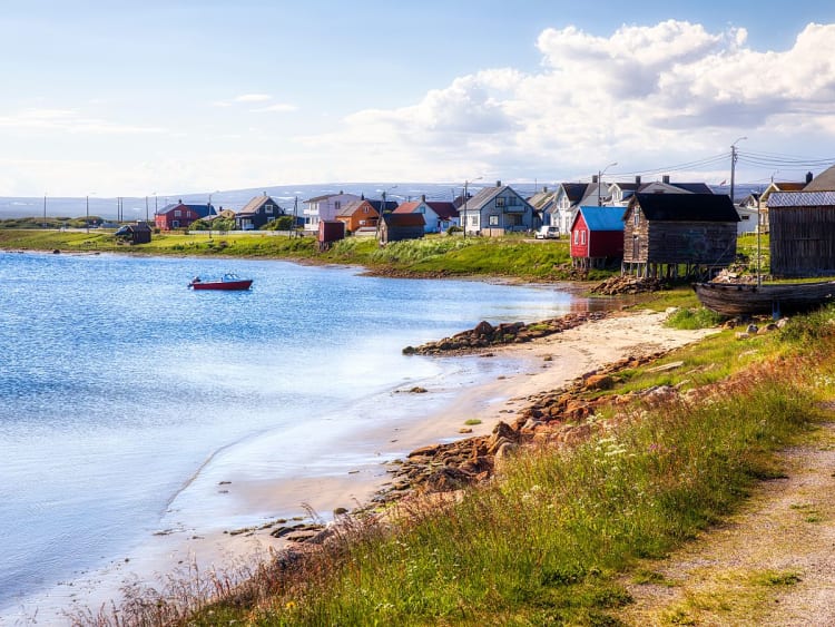 Vads&oslash;, Norwegen - Siedlung am Wasser mit Boot und Strand entlang der K&uuml;ste