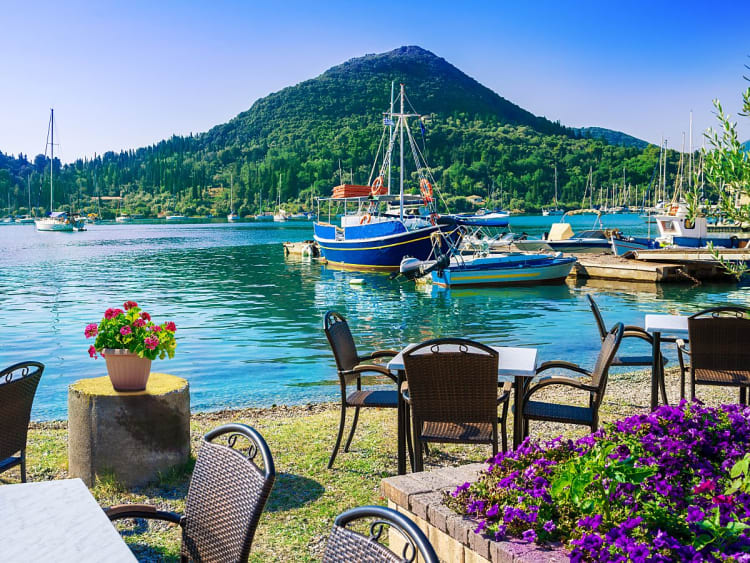 Nydri, Griechenland - Ufercaf&eacute; mit Blick auf Boote im ruhigen Hafen und bewaldeten H&uuml;gel