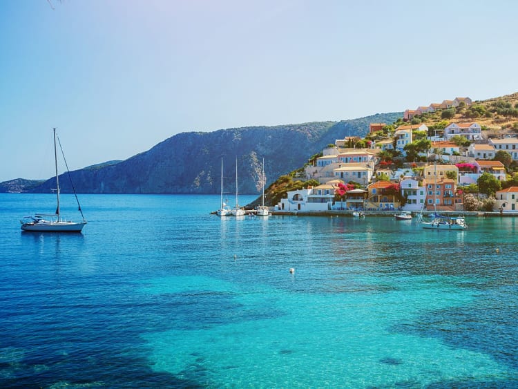 Nydri, Griechenland - K&uuml;stendorf mit pastellfarbenen H&auml;usern und Booten im klaren Wasser