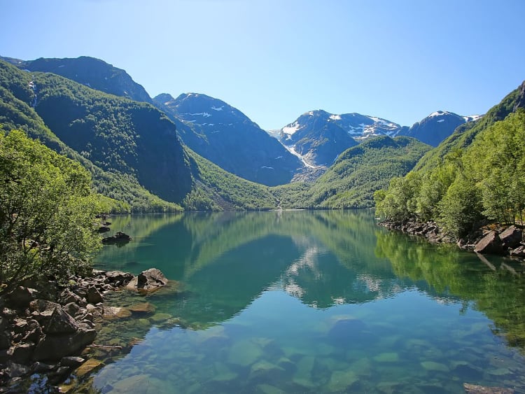 Rosendal, Norwegen - Ruhiger See vor Bergen mit Schnee und dichtem Wald