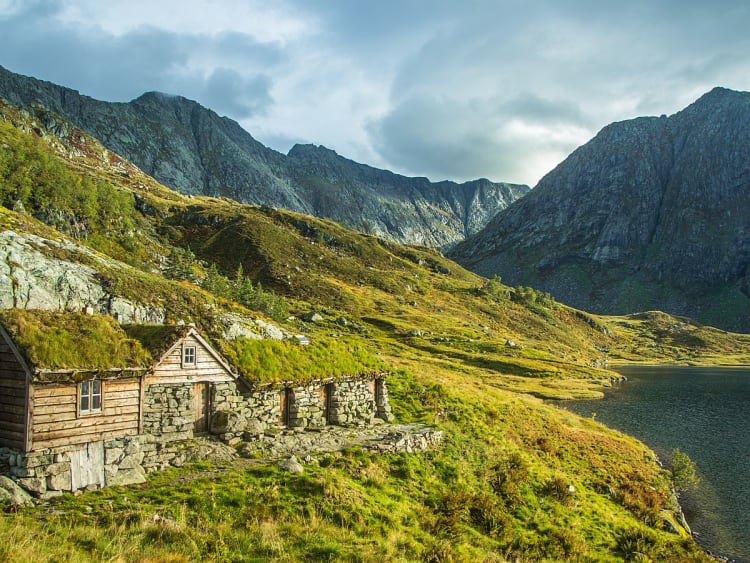 Rosendal, Norwegen - Bergh&uuml;tte am Seeufer vor steilen Felsen und Bergen