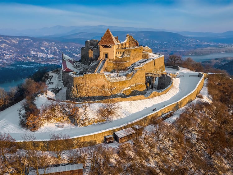 Visegr&aacute;d, Ungarn - Verschneite Burg auf H&uuml;gel &uuml;ber Donau im warmen Licht