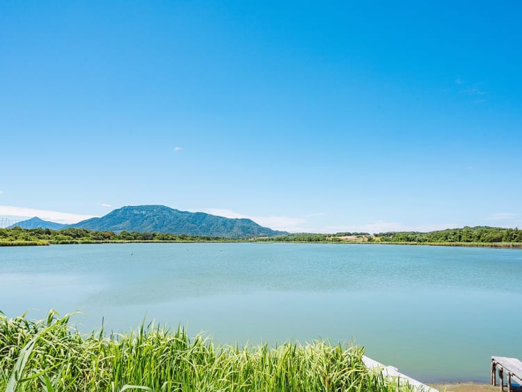 Sakata, Japan - Ruhiger See vor Bergkulisse unter klarem blauem Himmel