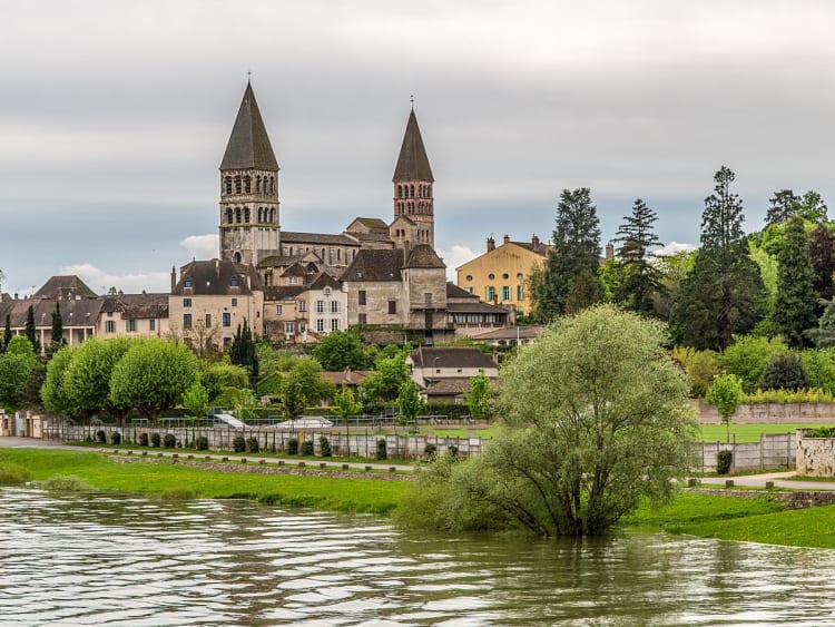 Tournus (Frankreich) - Blick auf Kirche und H&auml;user am Fluss mit gr&uuml;ner Landschaft