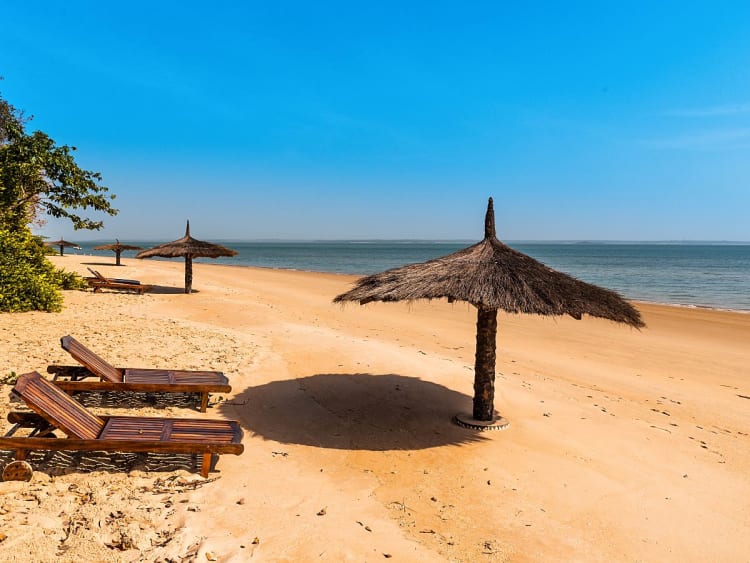 Banjul, Gambie &ndash; Plage de sable avec parasols en chaume sur la c&ocirc;te atlantique