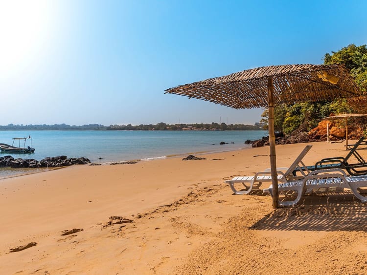 Banjul, Gambie &ndash; Plage de sable avec chaises longues face &agrave; la baie