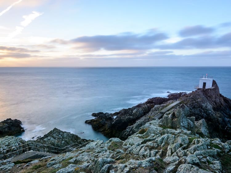 Guernsey, Ilhas do Canal &ndash; Farol sobre um promont&oacute;rio rochoso ao p&ocirc;r do sol