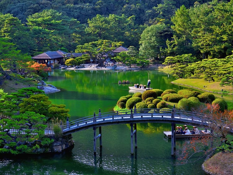 Takamatsu, Shikoku, Japan &ndash; Gebogen houten brug over een groene vijver