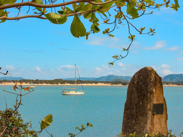 Cooktown, Queensland, Austr&aacute;lia &ndash; Veleiro em uma ba&iacute;a tranquila com monumento de pedra