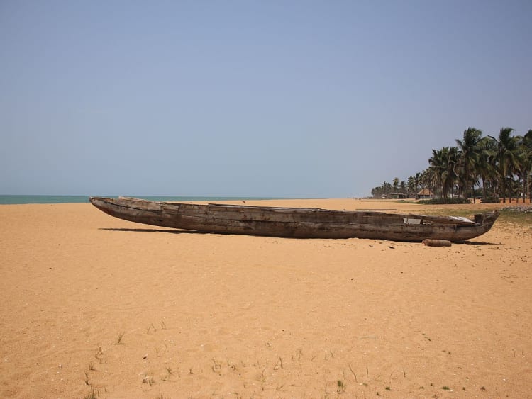 Lom&eacute;, Togo &ndash; Costa tropical com barco de madeira e coqueiros