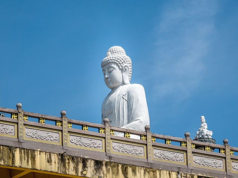 Port Klang, Malaysia &ndash; Wei&szlig;e Buddha-Statue ragt &uuml;ber Tempelmauern in den blauen Himmel
