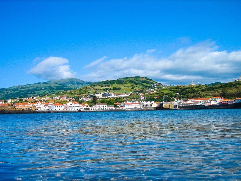 Horta, Azoren &ndash; wei&szlig;e H&auml;userzeile am Ufer mit gr&uuml;nen H&uuml;geln dahinter