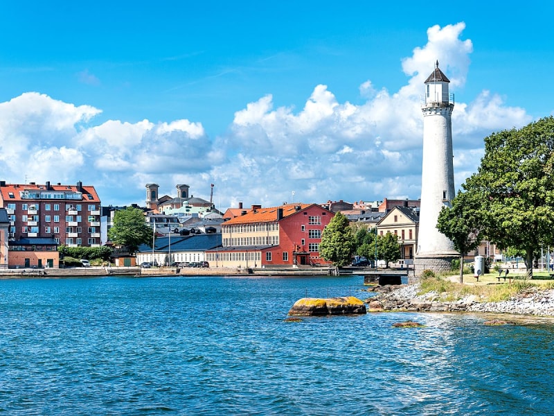 Karlskrona, Schweden &ndash; wei&szlig;er Leuchtturm vor bunten H&auml;usern am Ufer