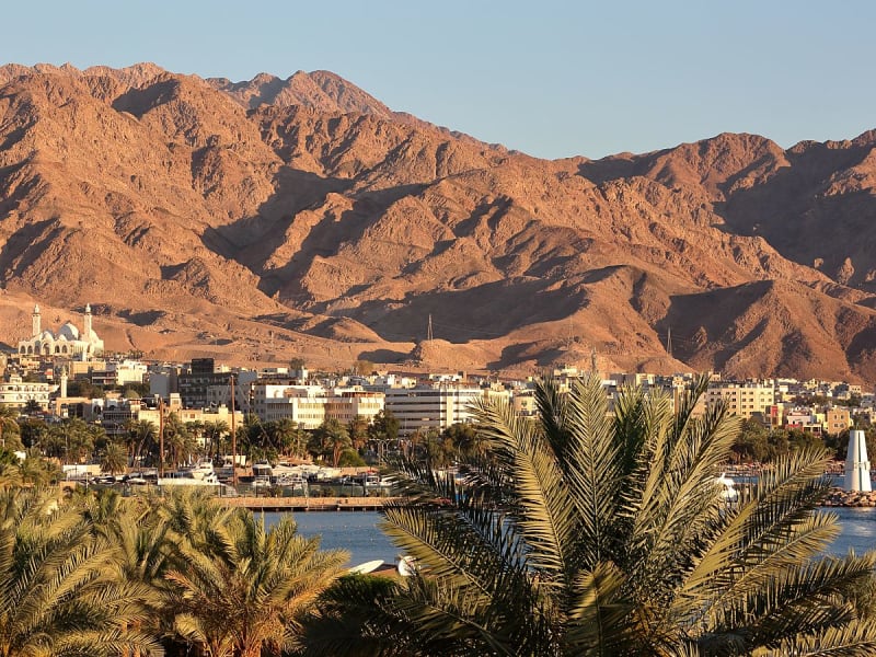 Aqaba, Jordanien &ndash; Stadtansicht mit Palmen und imposanten W&uuml;stenbergen im Hintergrund