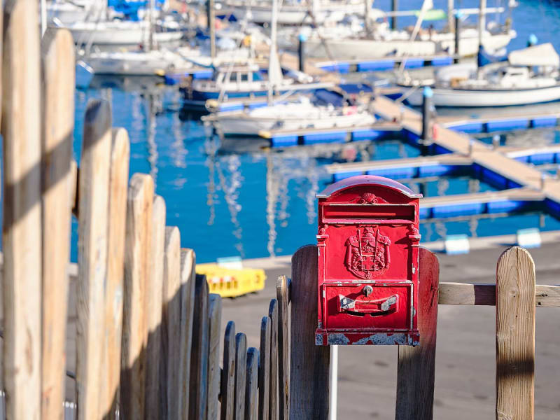 Puerto de la Estaca, El Hierro, Kanaren &ndash; Alter roter Briefkasten mit Yachthafen im Hintergrund