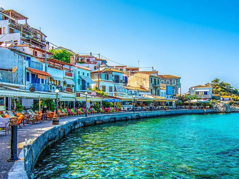 Samos (Griechenland) - Bunte H&auml;user und Caf&eacute;s s&auml;umen die Promenade am klaren Wasser