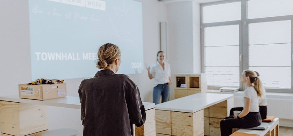 Mitarbeitende bereiten sich in einem hellen Raum auf eine Präsentation vor.