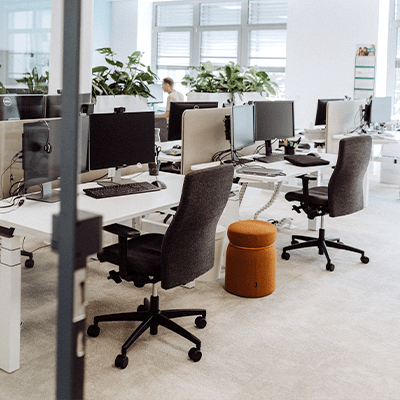 Ein heller Büroraum mit einer großen Fensterwand und Pflanzen