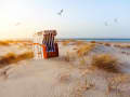Chaise de plage entre les dunes sous la lumière chaude du coucher de soleil sur la côte