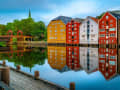 Trondheim, Norwegen – bunte Speicherhäuser spiegeln sich im ruhigen Fluss