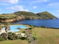 Isla Terceira, Azoren – Poolanlage mit Palmen und Blick auf Bucht und Hügel