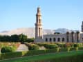 Maskat, Oman – Sultan-Qaboos-Moschee mit gepflegten Blumenbeeten und Bergen