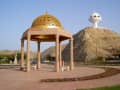 Maskat, Oman – Goldener Pavillon und weißes Weihrauchbrenner-Monument am Berg