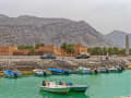 Khasab, Oman – Hafen mit kleinen Booten und historischer Festung vor karger Berglandschaft