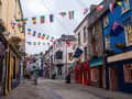Galway, Irland – Bunte Altstadtgasse mit internationalen Flaggen und farbenfrohen Hausfassaden