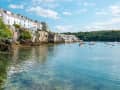 Fowey, England – Reihen heller Küstenhäuser am Wasser mit kleinen Booten im ruhigen Hafenbecken