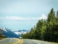 Anchorage, Alaska – Straße windet sich durch Wälder in Richtung verschneiter Berge