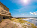Puerto Madryn, Argentinien – Strand mit Algen, Steilküste und sonnigem Himmel