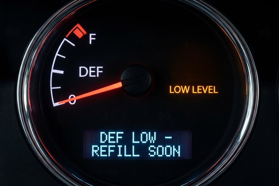 Semi truck dashboard DEF gauge showing a low-level amber warning light