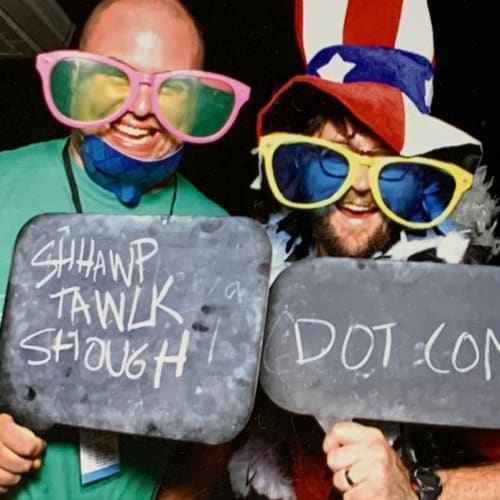 Chris Coyier and Dave Rupert in silly sunglasses and a sign that says Shawp Tawlkk Shough DOT COM