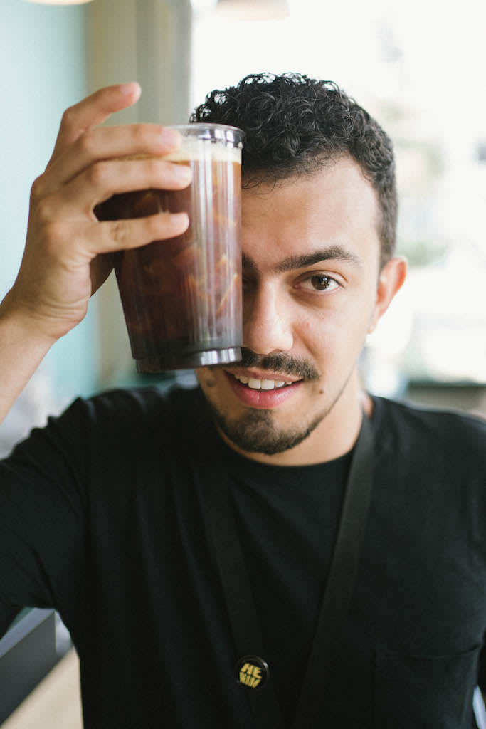 Jordan holding an iced coffee against his head to cool down