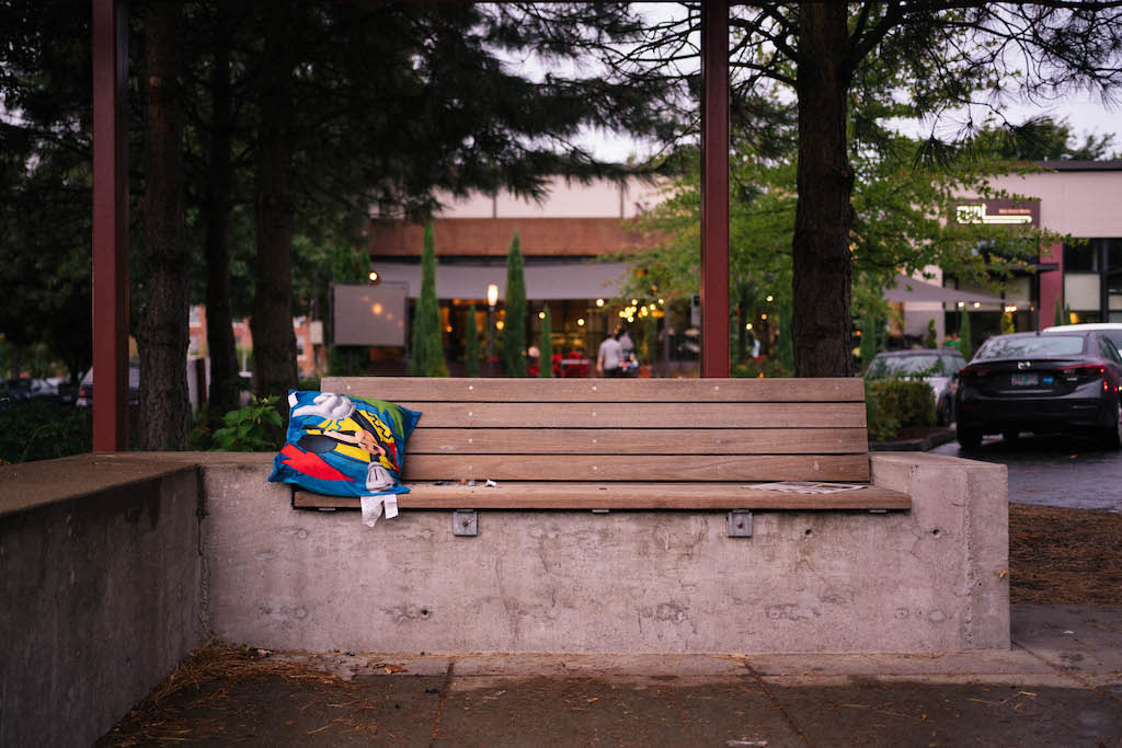 A kid's pillow left on the bench of a bus stop