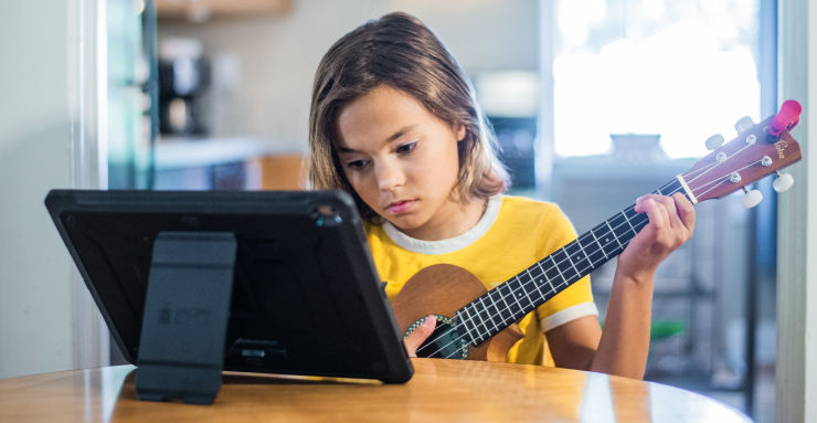 Kid playing ukulele at table