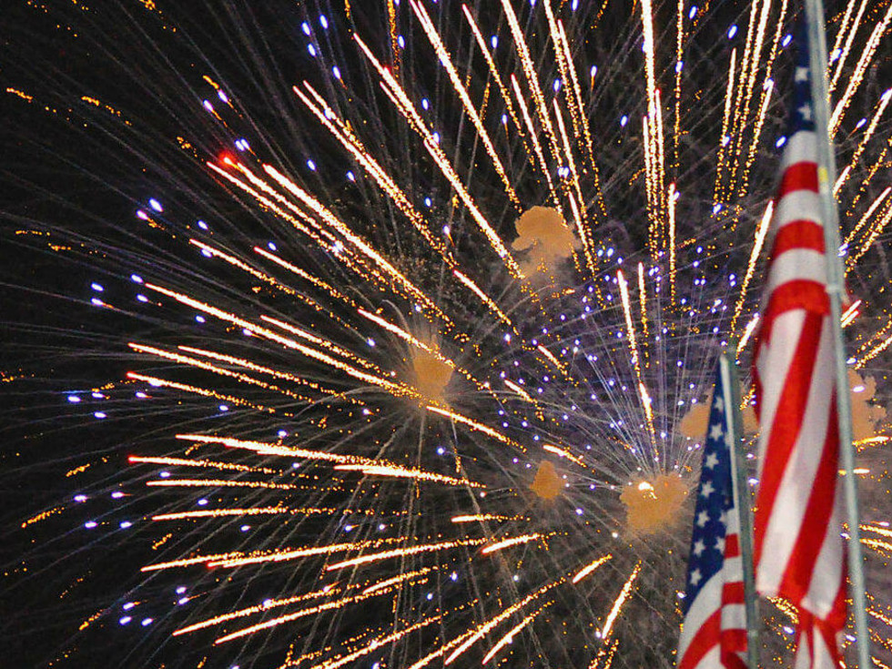 Fireworks behind U.S. flags flying at night, Addison, Texas.