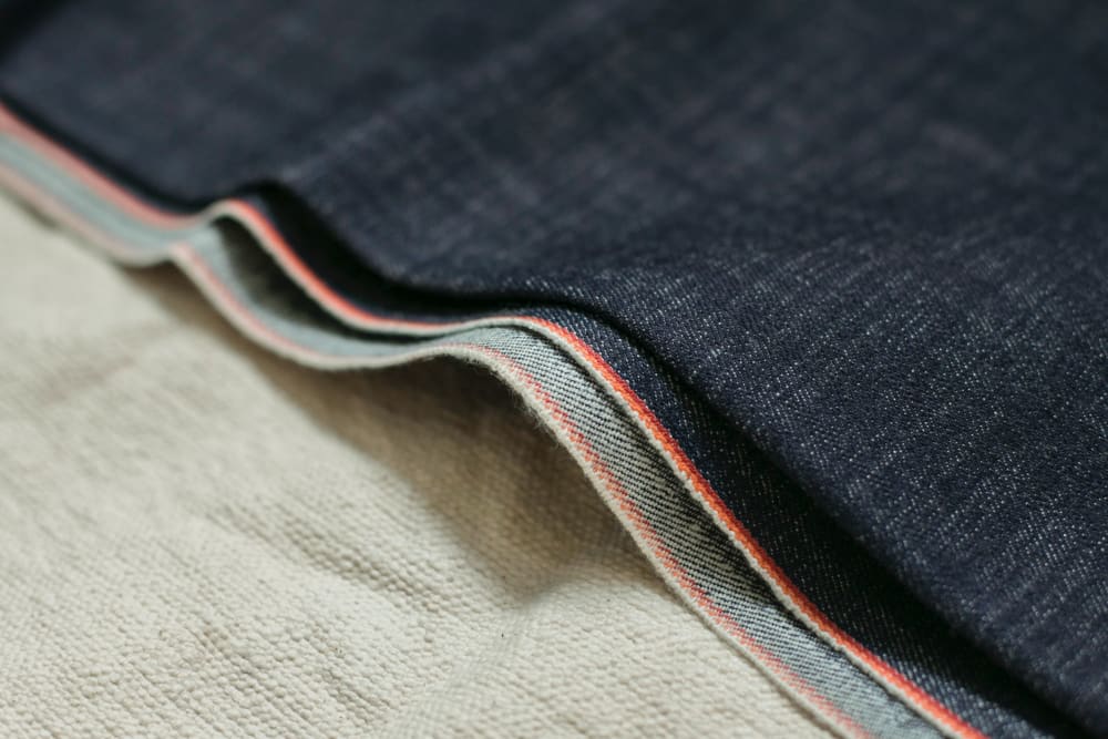 Different stages of denim cloth, showing its un-dyed cotton state and once it has been dyed with the classic indigo colour