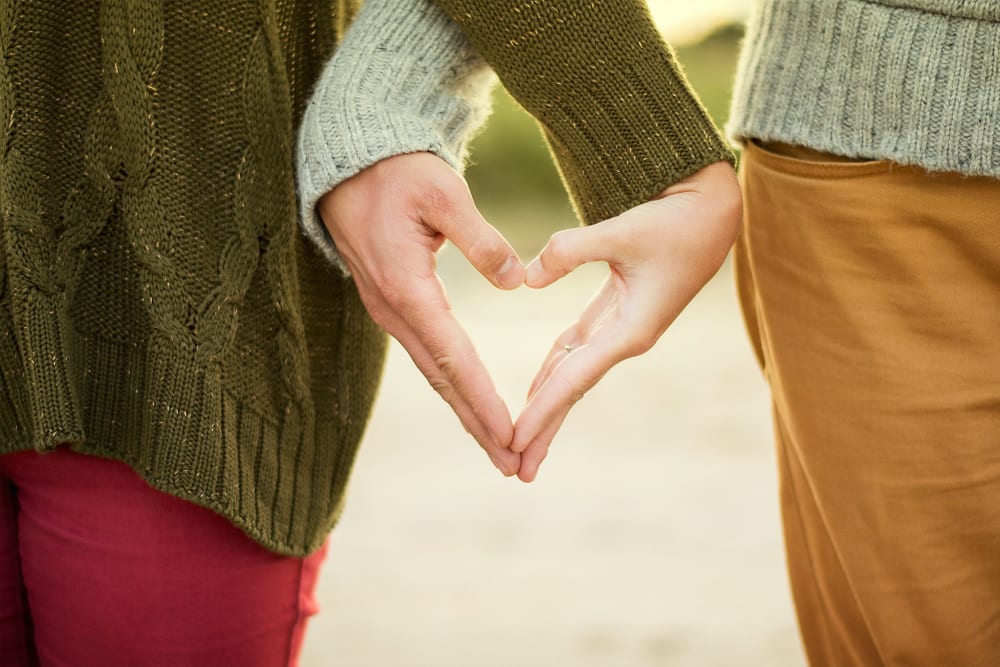 Two hands intertwined to create the shape of a love heart