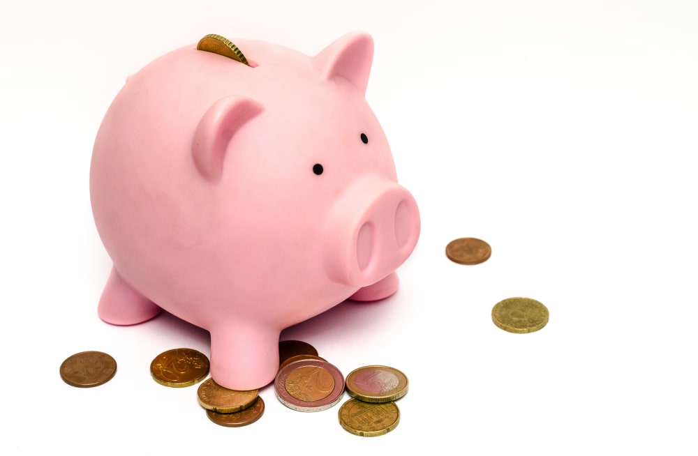 White background with a pink piggy bank surrounded by loose change