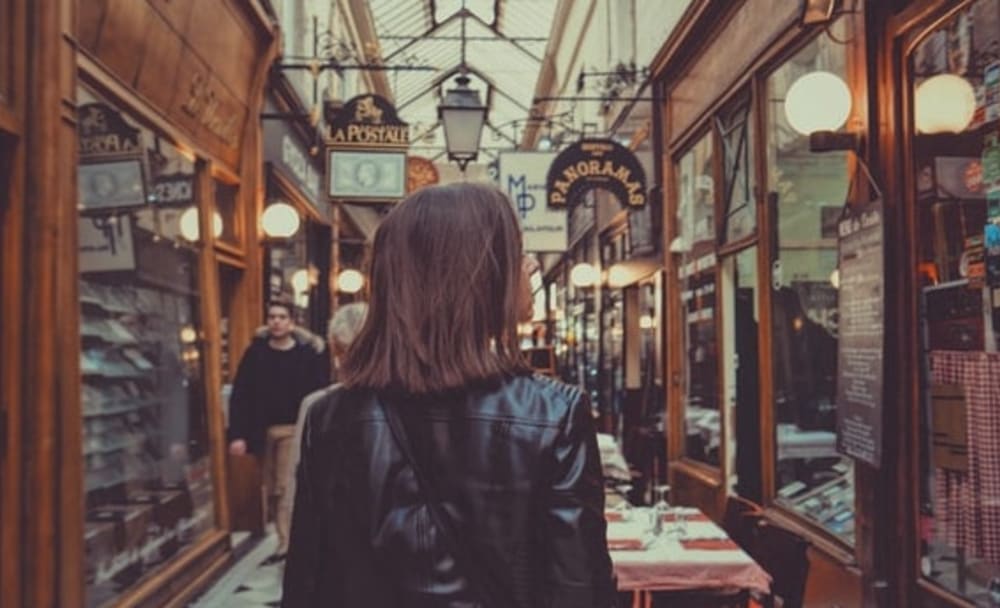 View of the back of woman's head standing in a small passageway full of boutique shops