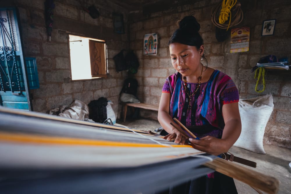 A garment maker at work in a basic brick building