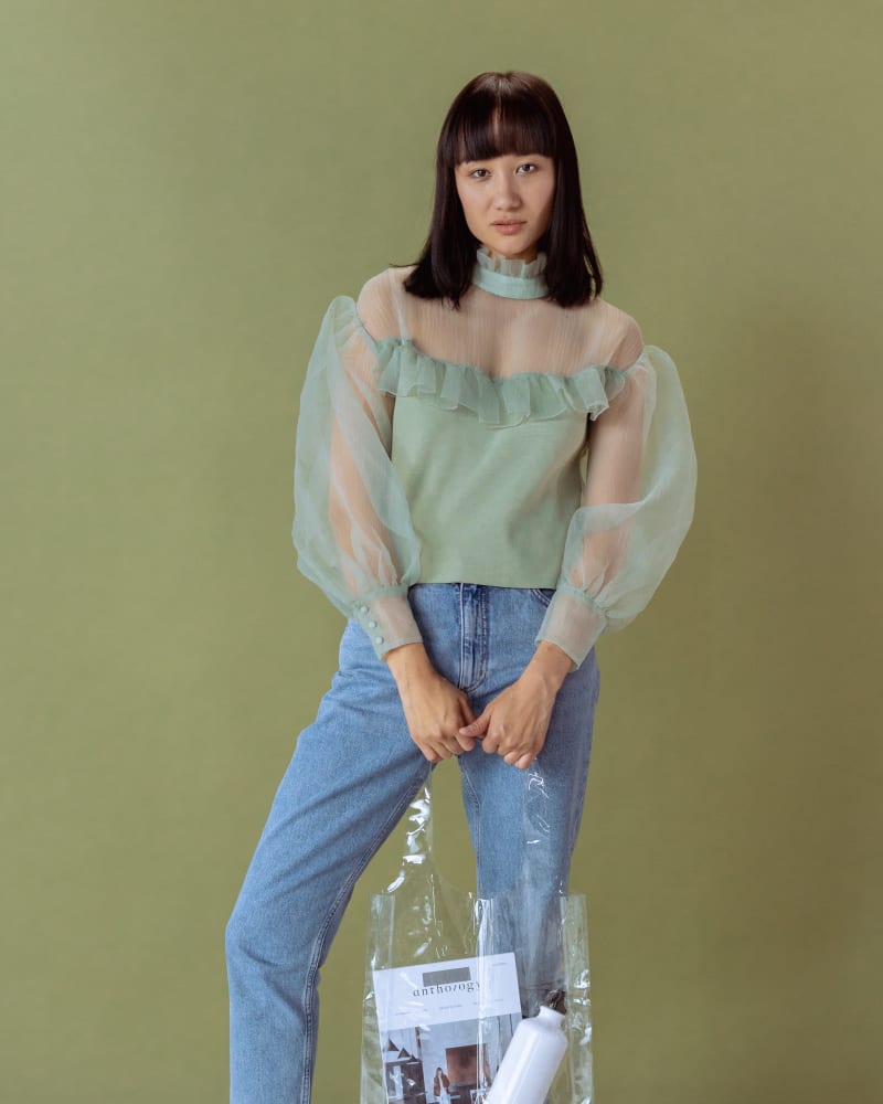 Photo of a Woman in a Green Top with puffed sleeves Holding a Clear Bag